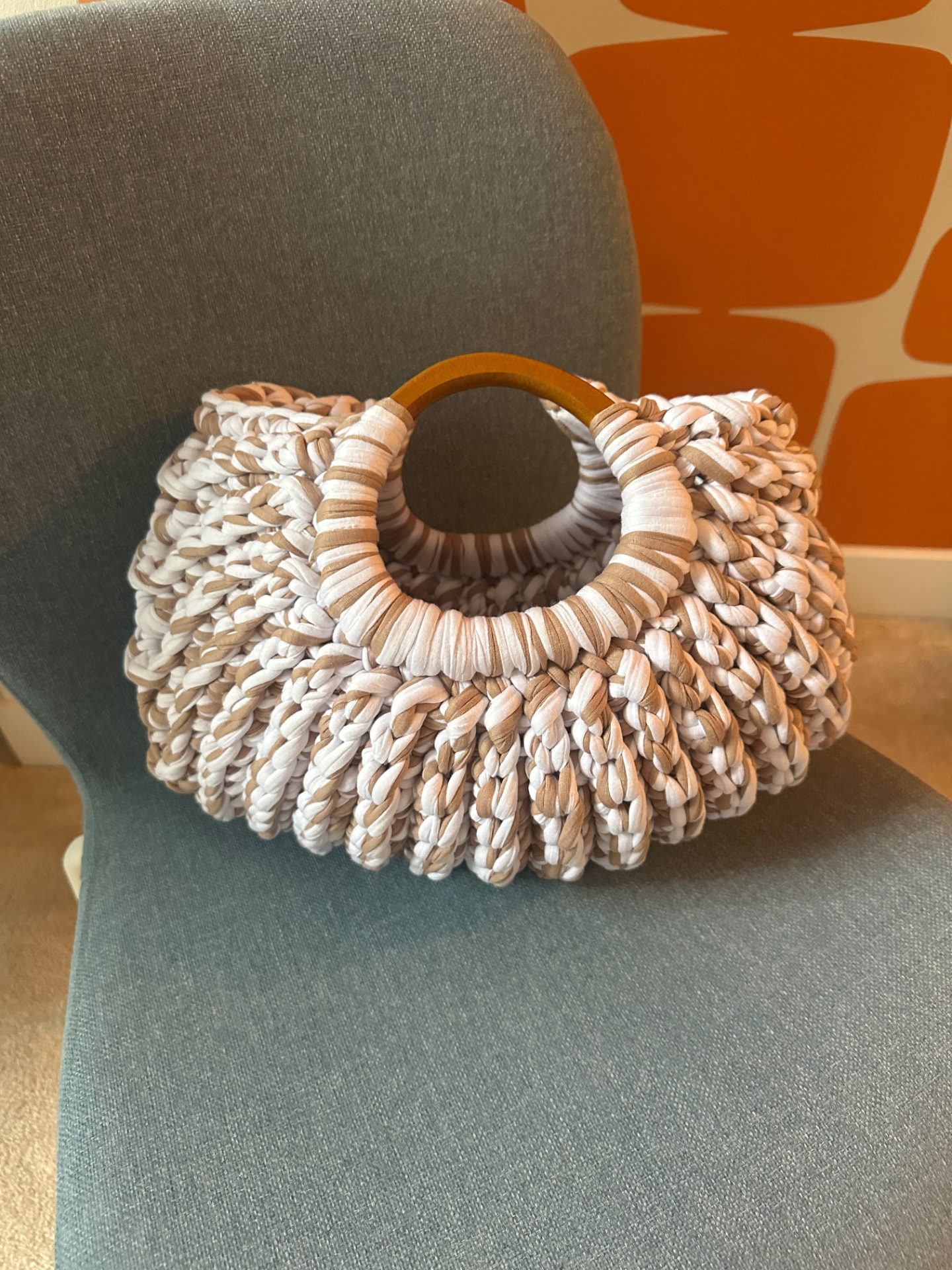 White and taupe Ripple Ring Bag on a chair