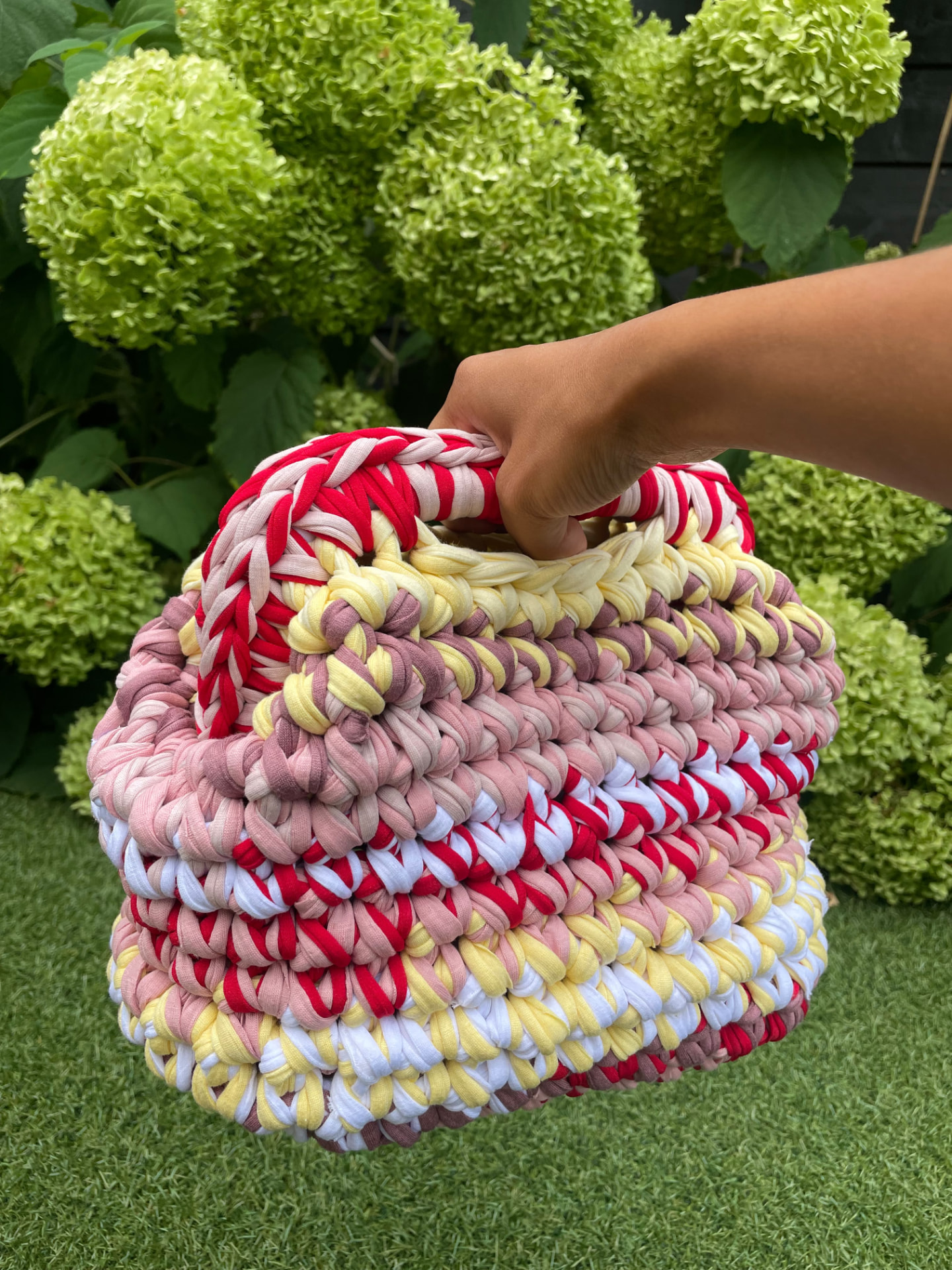 Colourful custom crocheted bag held outdoors